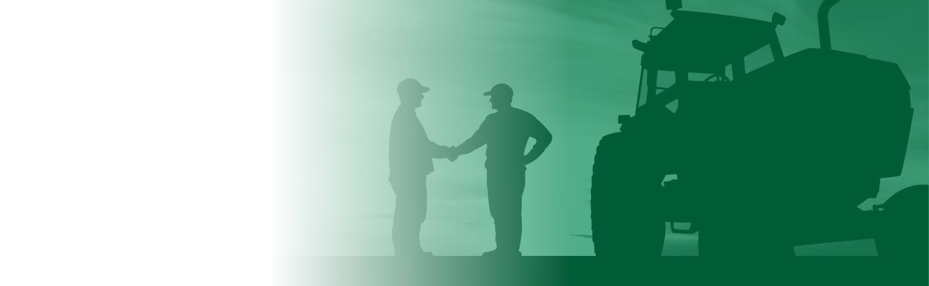 Picture of two men standing beside a tractor and shaking hands.